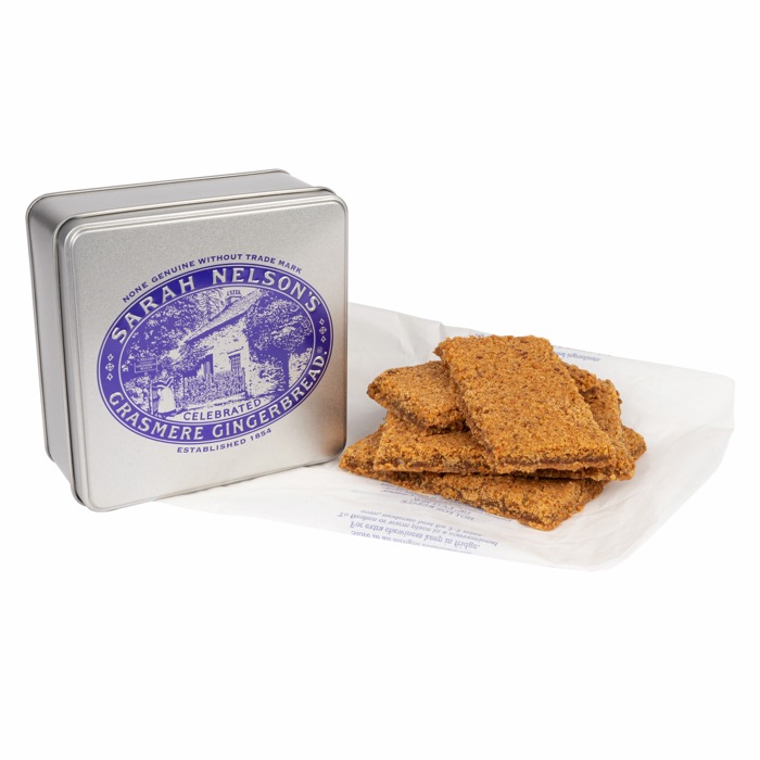An open tin of Grasmere Gingerbread with slices resting on waxed paper