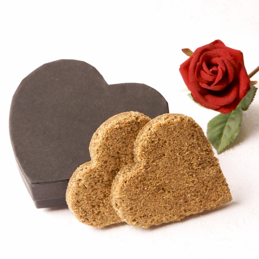 Heart-shaped Grasmere Gingerbread favours beside a dark heart-shaped gift box and a red rose